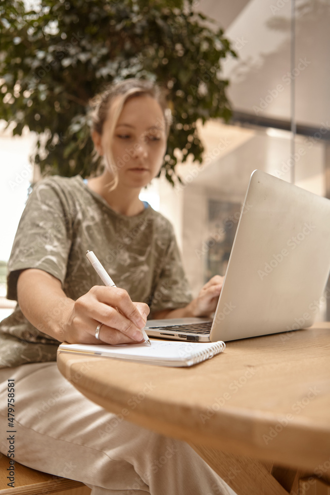 Portrait beautiful young woman sitting at table with laptop in cafe. Learning online, typing, search for information, notes of the synopsis. Portrait beautiful young woman sitting at table with laptop in cafe. Learning online, typing, search for information, notes of the synopsis.