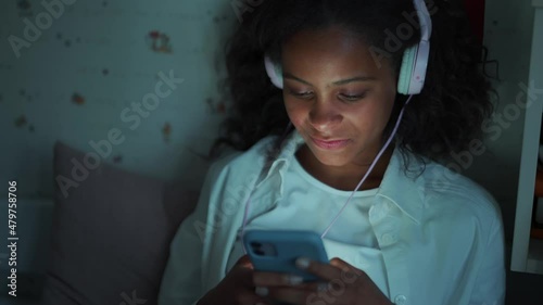 Wallpaper Mural Happy African young girl with headphones texting by mobile at home Torontodigital.ca