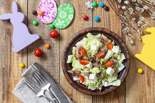 Holiday food, easter salad. Salad with chinese cabbage, feta, cherry tomatoes and canned tuna and vinegar dressing on a festive table. Top view flat lay.