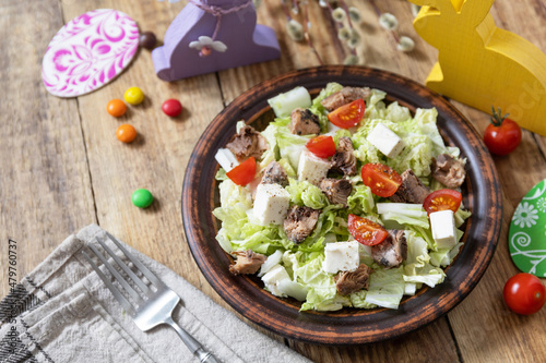 Holiday food, easter salad. Salad with chinese cabbage, feta, cherry tomatoes and canned tuna and vinegar dressing on a festive table. Copy space.