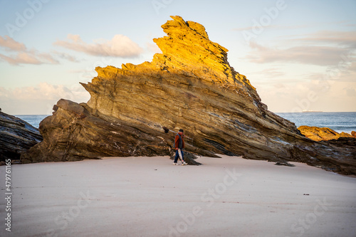A man with fishing equipment walking on the beach with beautiful rocks formations, Sines, Portugal photo