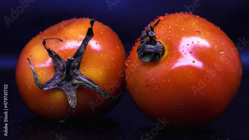 two fresh tomatoes in orange on black background