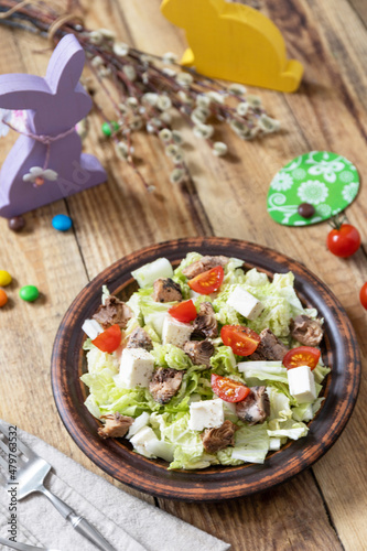 Holiday food, easter salad. Salad with chinese cabbage, feta, cherry tomatoes and canned tuna and vinegar dressing on a festive table.