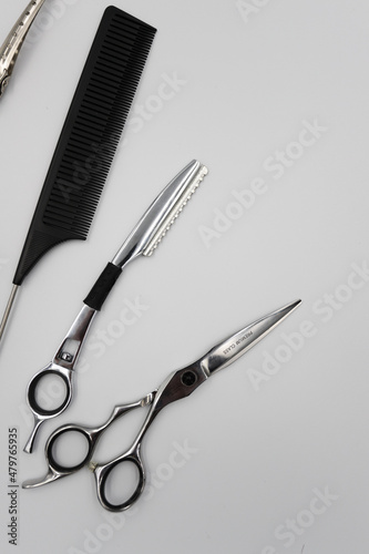 a set of professional combs, scissors, razors and hairpins unfolds on a light background
