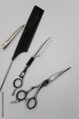 a set of professional combs, scissors, razors and hairpins unfolds on a light background