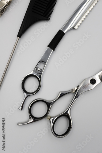 a set of professional combs, scissors, razors and hairpins unfolds on a light background
