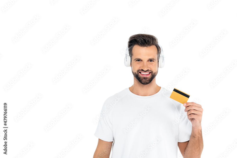 pleased man in headphones looking at camera while holding credit card isolated on white. pleased man in headphones looking at camera while holding credit card isolated on white.