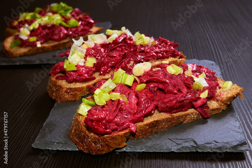 Homemade rye bread bruschetta with beetroot, herring, red and green onion salad. Traditional snack.