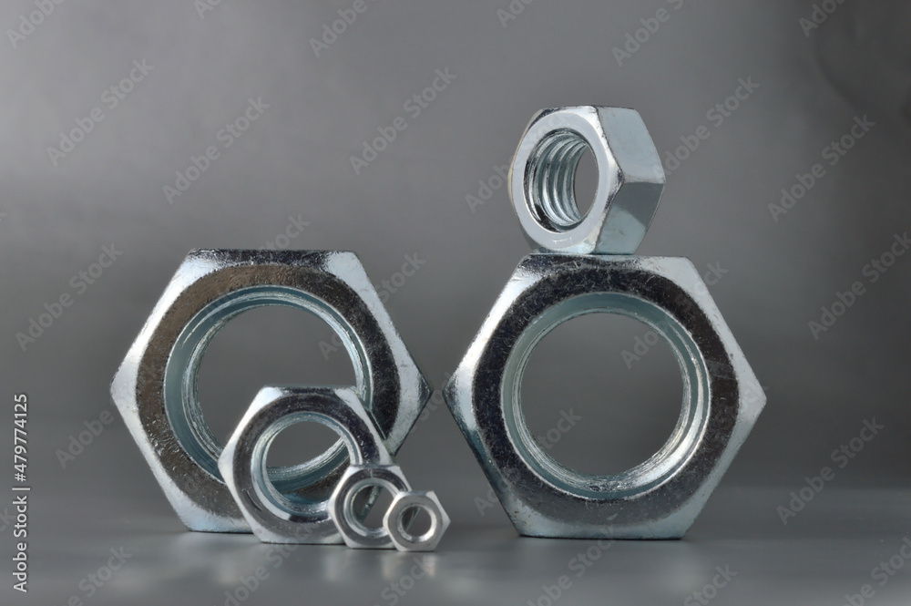composition of new bolts and nuts of different sizes on a gray background.