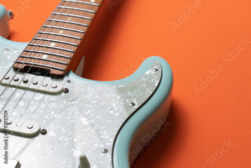 Electric guitar on orange table background, close up photo