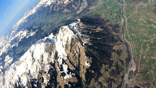 Skydiver in freefall above green mountainous landscape