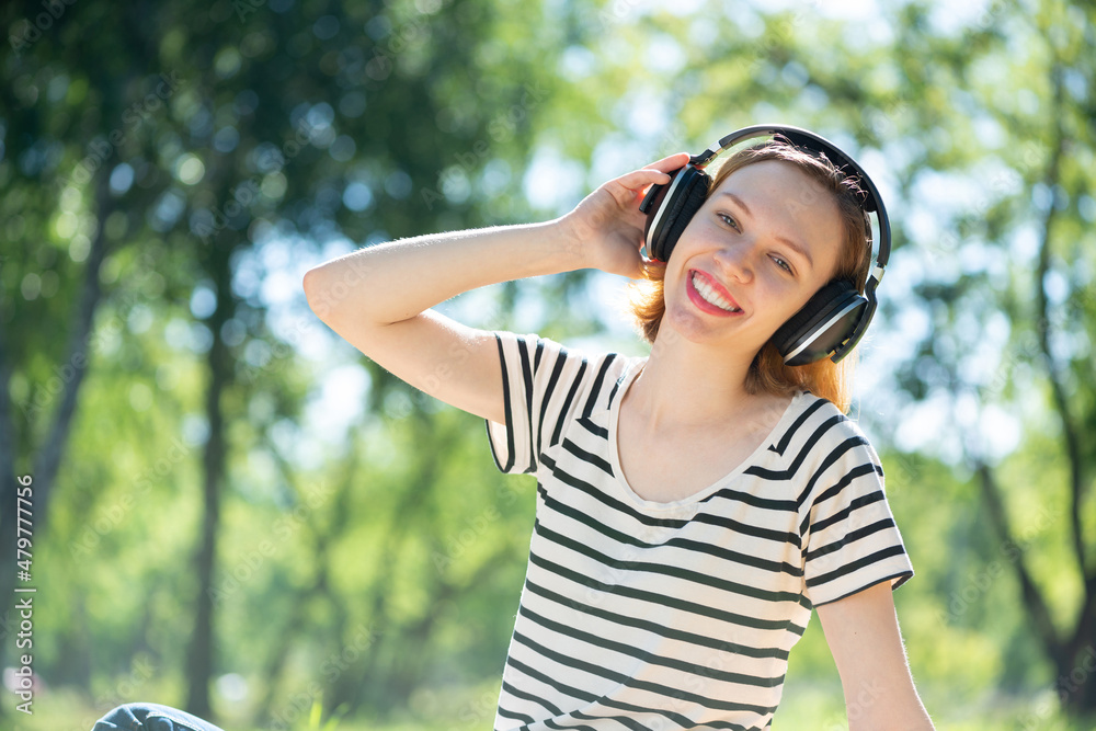 Young woman happens to have music in a summer park Young woman happens to have music in a summer park