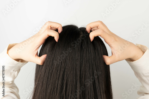 Woman scratching her head because of an itchy scalp. Causes of itchy includes dandruff, seborrheic dermatitis, psoriasis, Tinea capitis or allergy to hair care products. photo