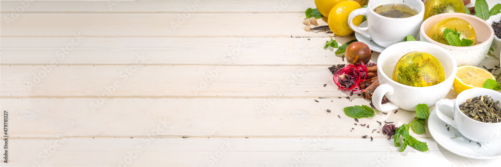 Various tea ball bombs. Assortment of different tea balls with dried tea, cups, lemon and mint, top view copy space. Trendy modern tea variety