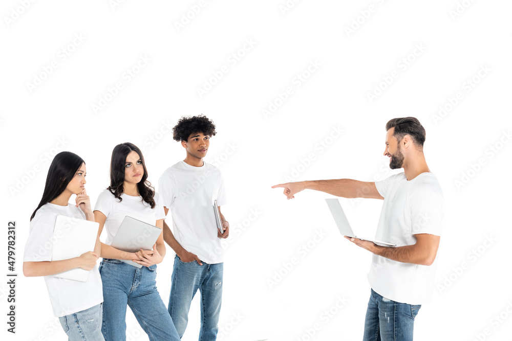 laughing man with laptop pointing at confused multiethnic freelancers isolated on white. laughing man with laptop pointing at confused multiethnic freelancers isolated on white.