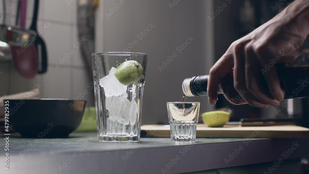 homemade of an alcoholic cocktail with ice, dark rum, lime and coca cola. pouring dark rum into a glass shot