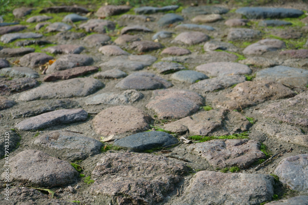 Natural background with stones. Beautiful rough stones structure in a decorative cover on the ground in close-up. Boulders as an antique, artistic, or vintage material for pavement in low-angle view.
