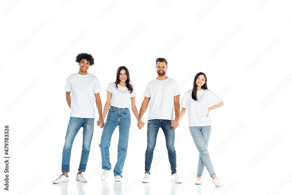 full length view of joyful interracial men and women holding hands while standing on white. full length view of joyful interracial men and women holding hands while standing on white.