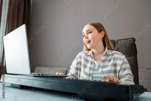 Canvas Print Woman learns music singing vocals playing piano online using laptop at home interior
