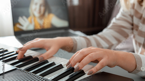Woman playing piano during video call via laptop. Female hands musician pianist improves skills playing piano online classes with teacher. Online Music education. Long web banner