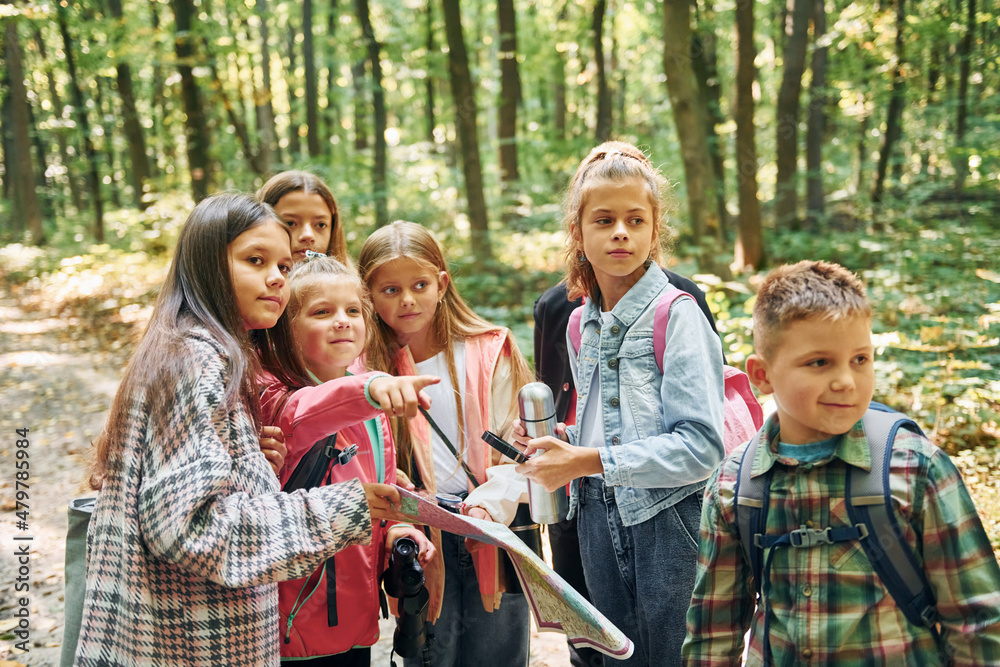 Fototapeta premium Front view. Kids in green forest at summer daytime together