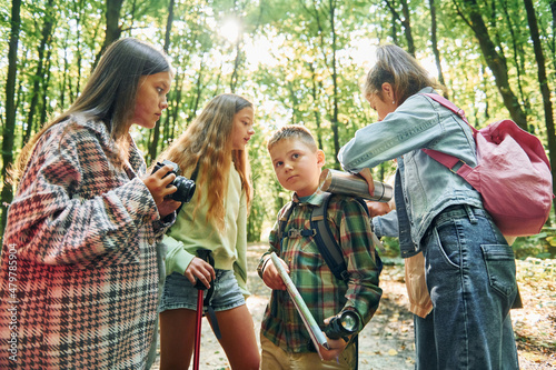 Standing together. Kids in green forest at summer daytime together