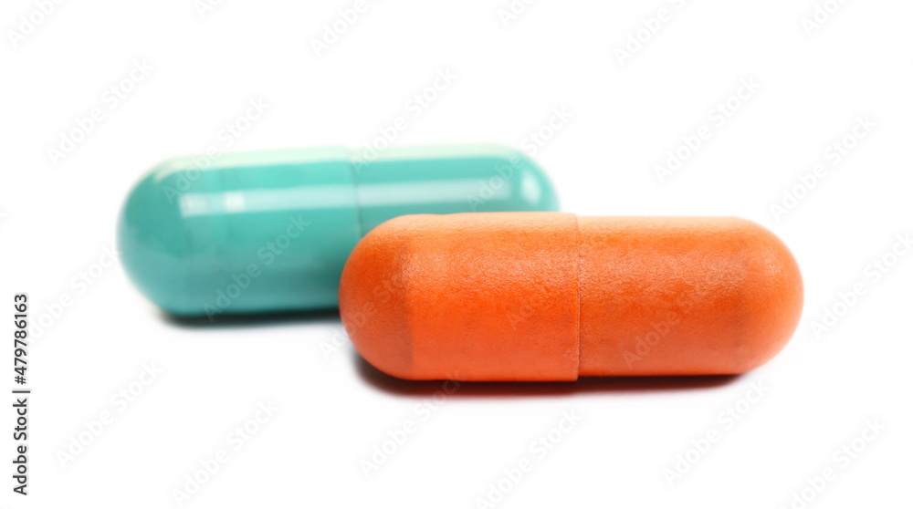 Orange and green pills macro, medicine isolated on white  