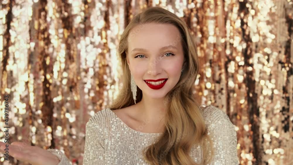 Fashion luxury portrait of woman sending blowing air kiss to the camera. Emotionally looking and smiling with red lips makeup, sparkling jewelry earrings on festive glittering background. Fashion luxury portrait of woman sending blowing air kiss to the camera. Emotionally looking and smiling with red lips makeup, sparkling jewelry earrings on festive glittering background.
