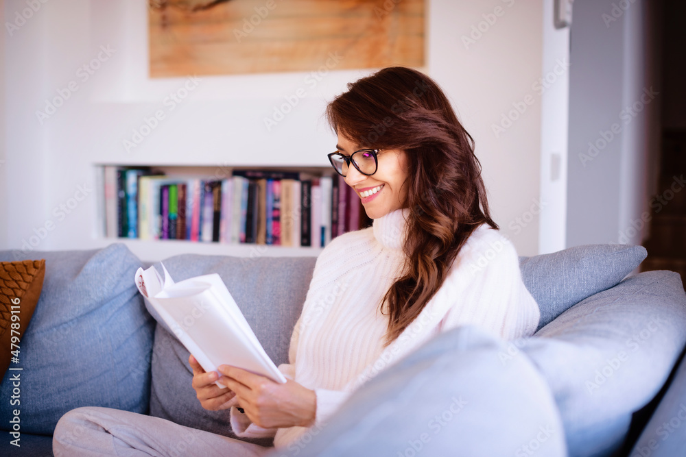 Attractive woman reading a book while relaxing at home Attractive woman reading a book while relaxing at home