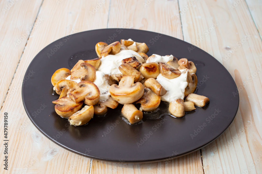 fried mushrooms with sour cream on a black ceramic plate