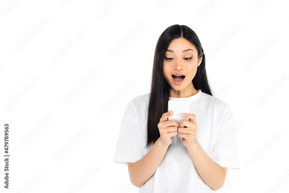 astonished asian woman in t-shirt looking at mobile phone isolated on white.