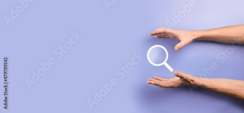 Male hand holding magnifying glass ,search icon on blue background. Concept search engine optimization, customer support.Browsing Internet Data Information.Networking Concept. © Ivan