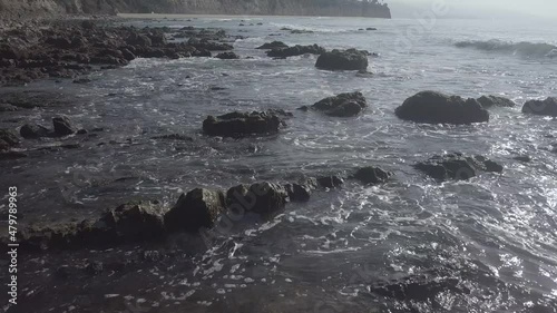 Waves crash over the rocky coast at sunset