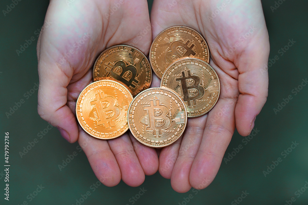 Bitcoin in the palms of a woman. Gold coins bitcoin stacked in the palms hands of a young woman on a dark background close-up. Crypto currency. Anonymous Bitcoin in the palms of a woman. Gold coins bitcoin stacked in the palms hands of a young woman on a dark background close-up. Crypto currency. Anonymous