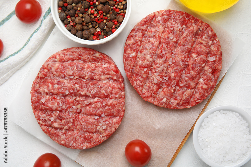 Raw hamburger patties with spices and tomatoes on white table, flat lay Raw hamburger patties with spices and tomatoes on white table, flat lay