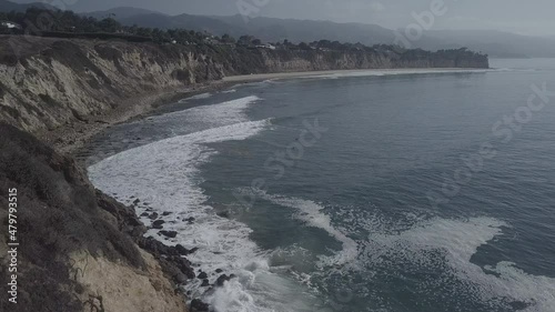 Wide drone shot of waves at the beach with surfers floating in the water photo