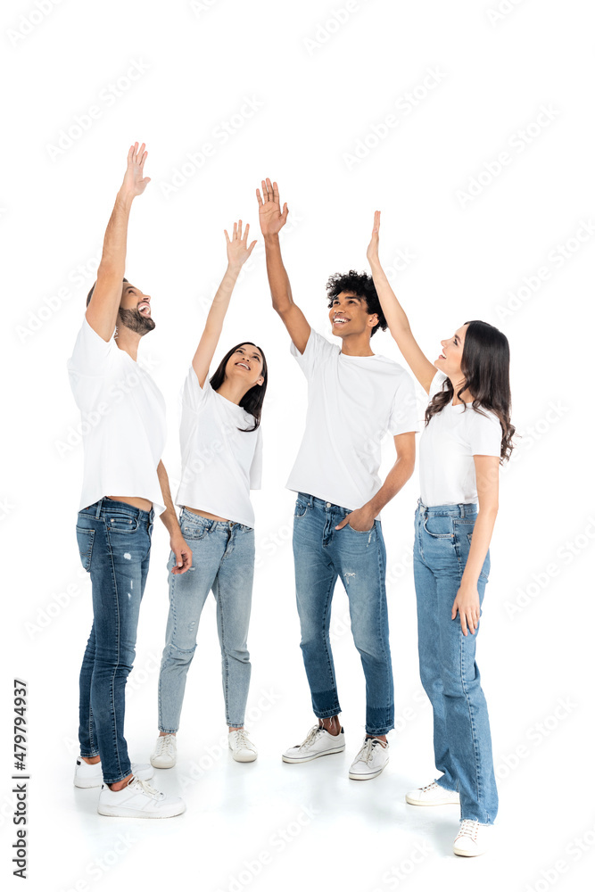 full length view of cheerful multicultural friends standing with raised hands while reaching something on white. full length view of cheerful multicultural friends standing with raised hands while reaching something on white.