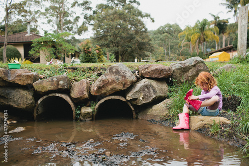 Girl exploring a stormwater drain in gumboots photo