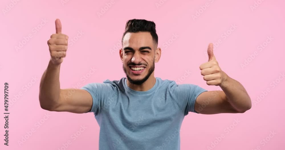 Excited man giving thumbs up gesture with both hands over pink background Excited man giving thumbs up gesture with both hands over pink background
