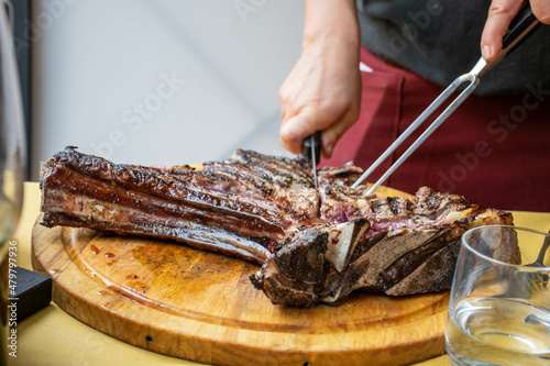 Fototapeta Pisa, Italy, September 2015, a woman's hands cut a Florentine steak