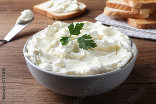 Tasty cream cheese with parsley on wooden table