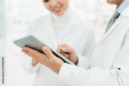 Closeup cropped shot of two female and male chemists pharmacists druggists using digital tablet for selling medicines, pills, remedies, learning new goods side effects in pharmacy drugstore © InsideCreativeHouse