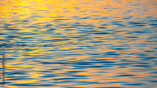 Reflection of the setting sun in a wave of water. Natural background texture