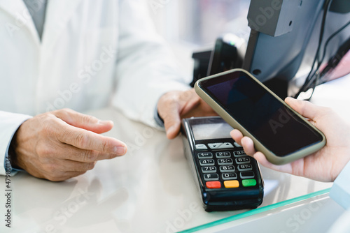 Blank screen of cellphone. Cashless wireless payment with mobile phone with mockup, copyspace at drugstore pharmacy at cash point desk, buying medicines, drugs, pills, e-commerce