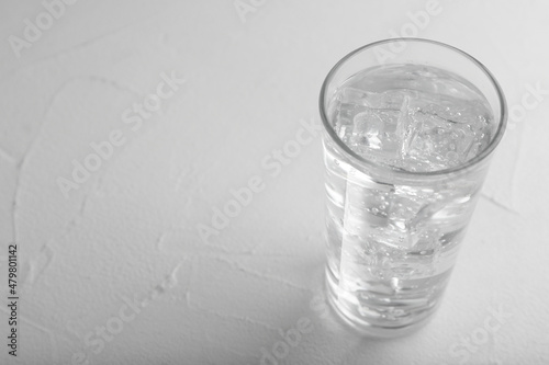 Glass of soda water on white table. Space for text