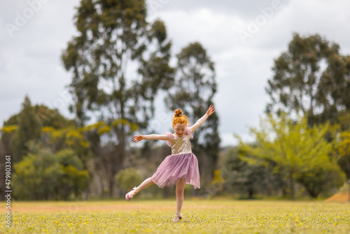 little red-haired girl dancing in a park