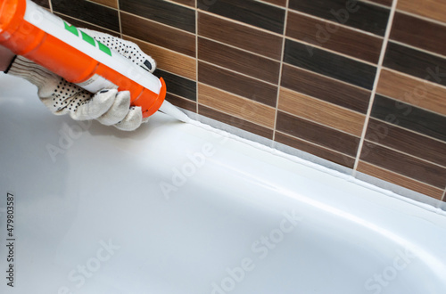 Sealing the bathroom with silicone sealant. Close-up. Renovation and decoration in the bathroom. Sealing seams photo