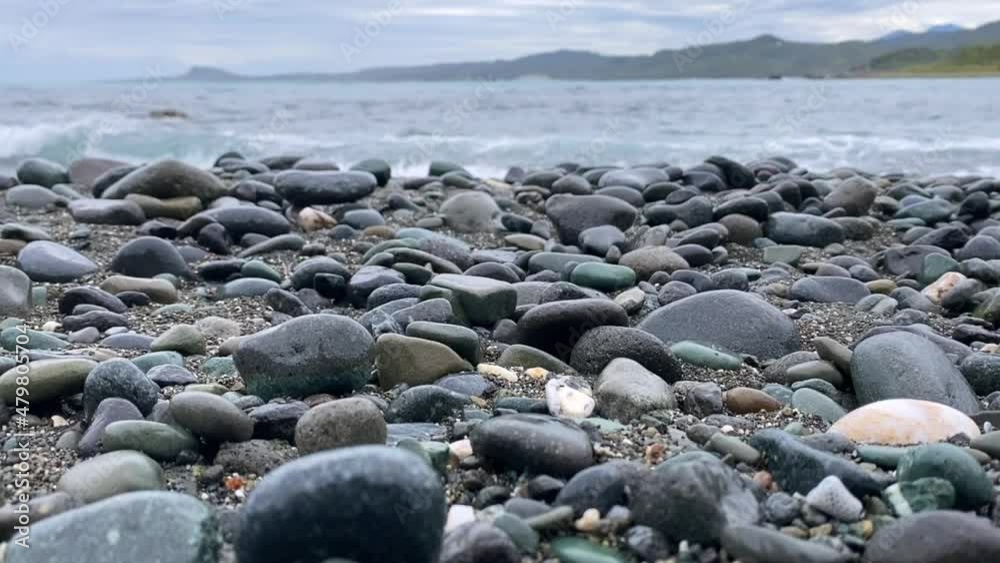 Waves hit the rocky beach with mountains behind on a cloudy day in Hualien city, Taiwan. Waves hit the rocky beach with mountains behind on a cloudy day in Hualien city, Taiwan.