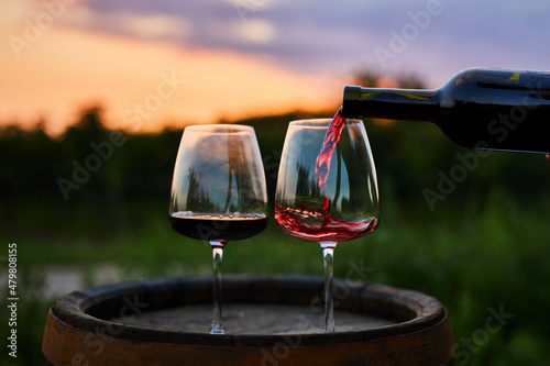 Pouring red wine from a bottle into a glass at dusk