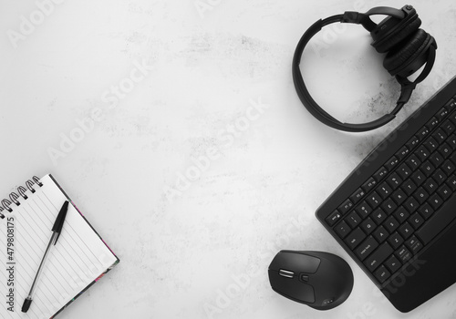 Computer keyboard, wireless mouse, bluetooth on-ear or over-ear headphones, notebook, pen. Flat lay composition, office work or working from home concept with copy space. Workplace desk, workspace.